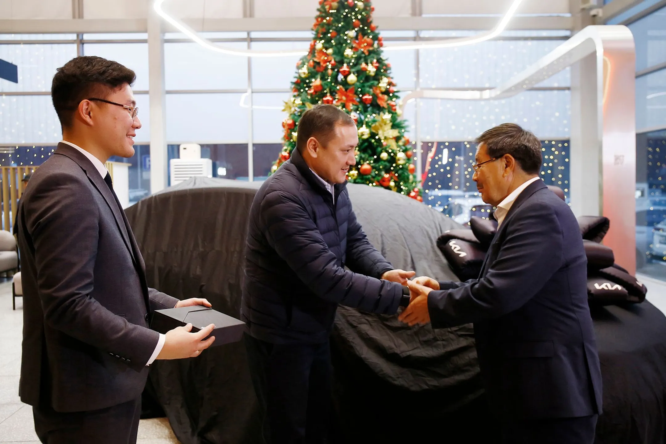 На фото: глава ForteLeasing Талап Рахманов и менеджер отдела продаж дилерского центра Kia Жаслан Карменов вручают ключи от машины Арману Баймолдаеву 